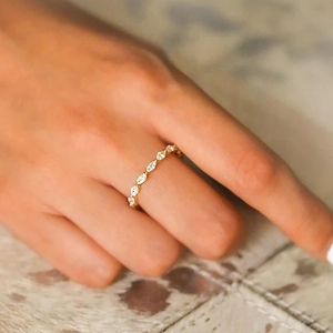 Macro shot of a gold-plated marquise cut diamond band worn on a finger