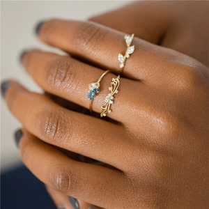 Close-up of three gold rings with blue gemstones and diamonds worn by a model