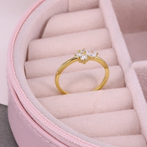 Close-up of a thin gold ring with four white crystals in a pink velvet jewelry box