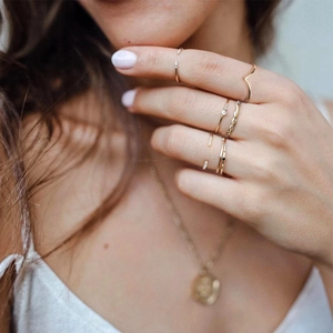 Close-up of stacked gold-plated rings with zircon accents on fingers in lifestyle setting