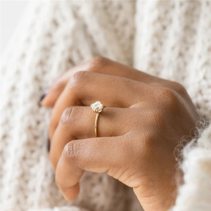 Detailed close-up of a square-cut diamond ring on a gold band worn by a model
