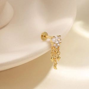 Detailed close-up of gold labret stud with pink opal stones and celestial tassel charms