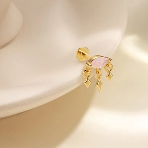 Macro detail of gold labret stud with marquise pink opal and three star dangles