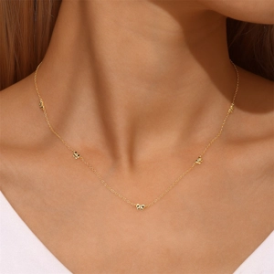 Gros plan d'une chaîne minimaliste en argent S925 doré avec cinq pendentifs nœuds délicats
