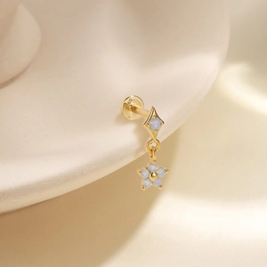 Macro detail of S925 gold-plated labret stud with blue opal flower tassel dangle