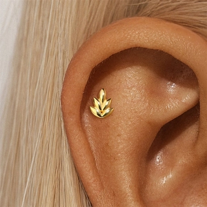 Detail of golden marquise leaf stud earring worn on ear with polished finish