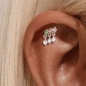 Macro detail of S925 silver cartilage stud with three colorful gems and zircon pendants
