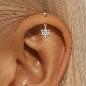 Macro detail van een gouden cartilage piercing sieraad met een fonkelende bloem van zirkonia