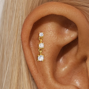 Detailed close-up of a triple round zircon flat back stud earring on a human ear