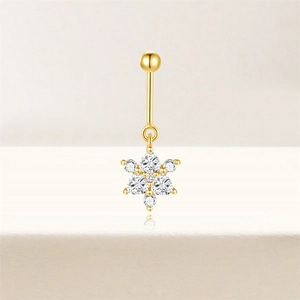 Detailopname van gouden navelpiercing met sprankelende witte zirkoon sneeuwvlokken