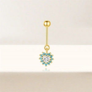 Macro detail van gouden navelpiercing hart met zirkonia en turquoise kralen