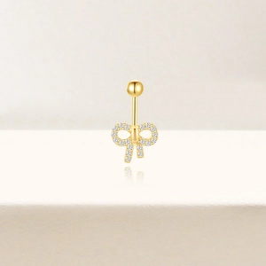 Macro detail van de gouden strik navelpiercing met sprankelende witte zirkonia steentjes