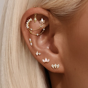 Detailed view of layered gold ear piercing set with crystals and chain dangle