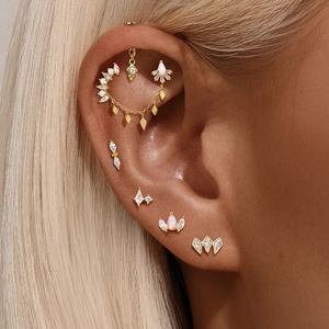 Close-up of golden S925 silver ear piercing set with marquise stones and opals on ear