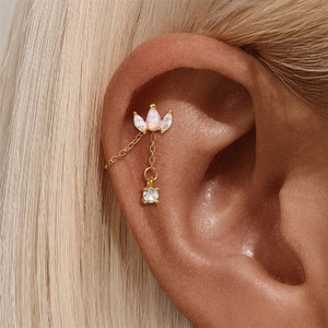 Close-up of gold drop opal earring with zircon accents and fine chain dangle on ear