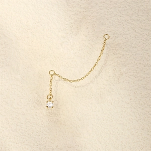 Detailed close-up of 18K gold chain earring component with four-prong set white zircon stone