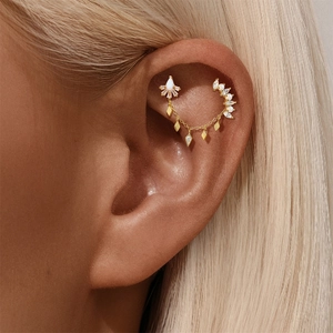 Detail of bohemian gold drop earring with opal stones and diamond charms on model ear