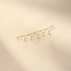 Detailed macro of gold chain dangling five geometric diamond charms with zirconia