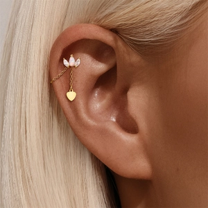 Detail of gold star and heart drop earrings with opal stud and long chain on model