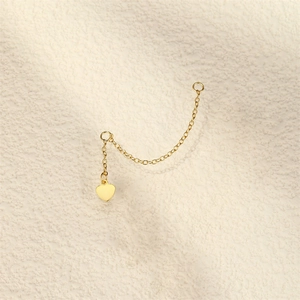 Detailed view of a golden chain link with dual rings and a polished heart pendant