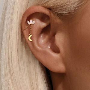Detail of gold star and moon cartilage earring with opal and marquise zircon on model