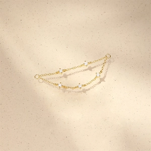 Detail of elegant gold double-layer chain earrings with five clear round zircon gemstones