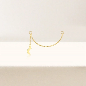 Macro detail of gold-plated chain earring accessory featuring a polished crescent moon pendant