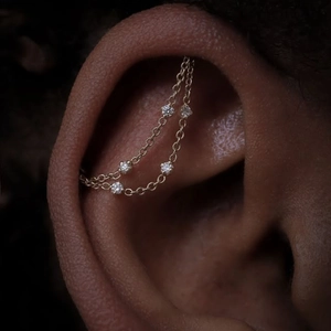 Macro shot of double-layer gold chain earring featuring five sparkling white crystals