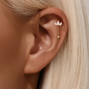 Detail of gold cartilage earring with marquise gemstones and a delicate star drop chain