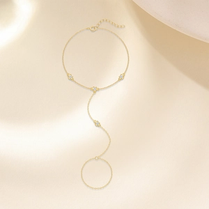 Detalle de una cadena de mano dorada con cuatro piedras de circonita redonda clara