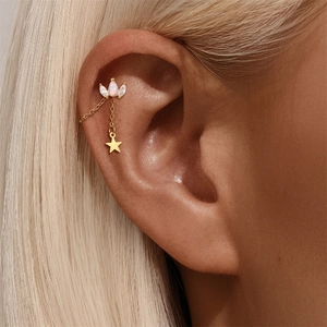 Detail of gold star drop earring with teardrop opal and marquise zircon on a model