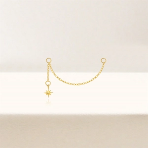 Detail of gold star pendant earrings with a long delicate chain connector on a light base