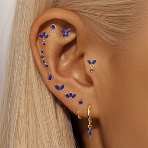 Macro view of blue lapis earrings set worn on ear featuring butterfly and floral studs