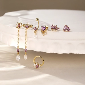 Detailed macro view of gold-plated jewelry set with purple marquise gems on stone base