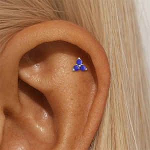Macro view of a triple blue lapis stone stud earring on an ear cartilage piercing