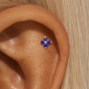 Detailed macro view of S925 golden clover stud earring with blue lapis lazuli on the ear helix