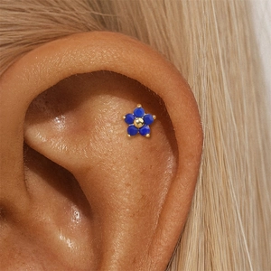 Close-up of blue five-petal flower stud earring with gold core on model ear
