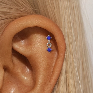 Macro view of sterling silver cartilage earring with blue lapis lazuli stones on ear