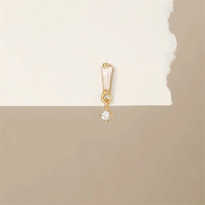 Detail eines goldenen Hängeohrrings mit trapezförmigen und runden Kristallen auf weißem Karton