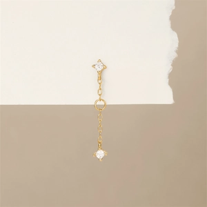 Detail eines goldenen Piercings mit quadratischen Zirkonia und feiner Kettenverzierung