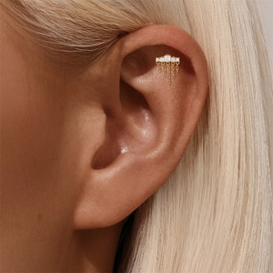 Detail eines goldenen Helix-Piercings mit drei Zirkonia-Steinen und feinen Kettendetails