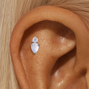 Detail of s925 silver ear piercing jewelry with natural moonstone on a real ear