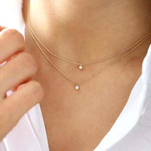 Detail of a gold double-layer necklace featuring sparkling round zircon pendants on neck