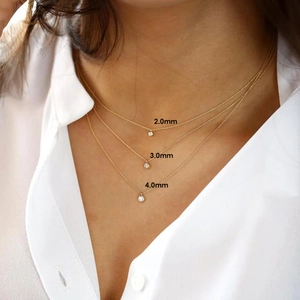 Detailed view of layered gold necklaces with 2.0mm, 3.0mm, and 4.0mm round diamond pendants