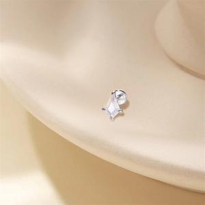 Macro shot of S925 sterling silver kite-cut moonstone earring on a beige display