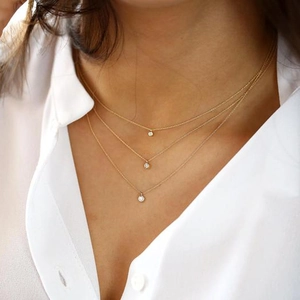 Close-up of triple-layered 18K gold plated necklaces with round solitaire zircon pendants