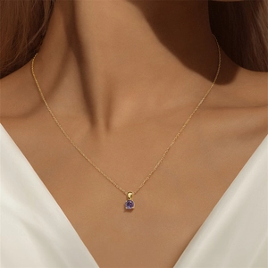 Detail van een paarse edelsteen hanger aan een gouden ketting gedragen door model