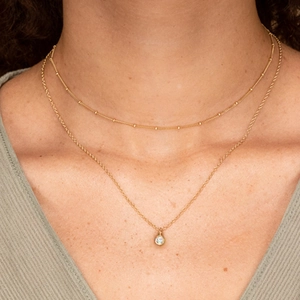 Detail of layered S925 silver necklaces with a sparkling solitaire zircon pendant