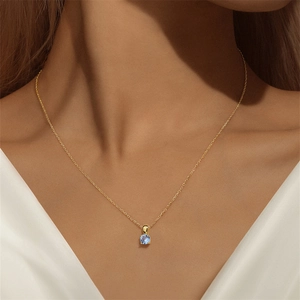 Detail van een 925 zilveren gouden ketting met een ronde lichtblauwe edelsteen hanger