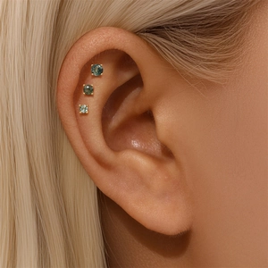 Detail of three s925 gold-plated ear studs with natural green moss agate on a model